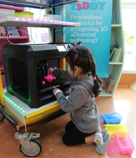 Una piccola paziente del Meyer stampa un oggetto in 3D con la stampante tridimensionale