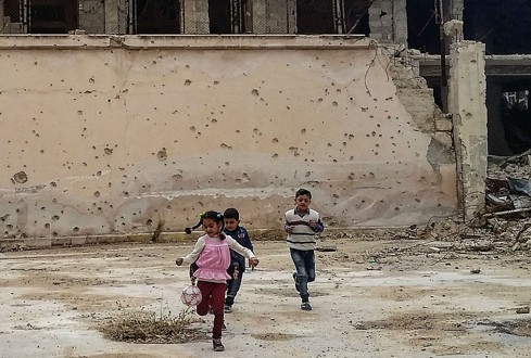 Foto di tre bambini che giocano a palla per le strade di Aleppo