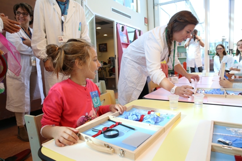 Foto bambina con microscopio in ludoteca al Meyer